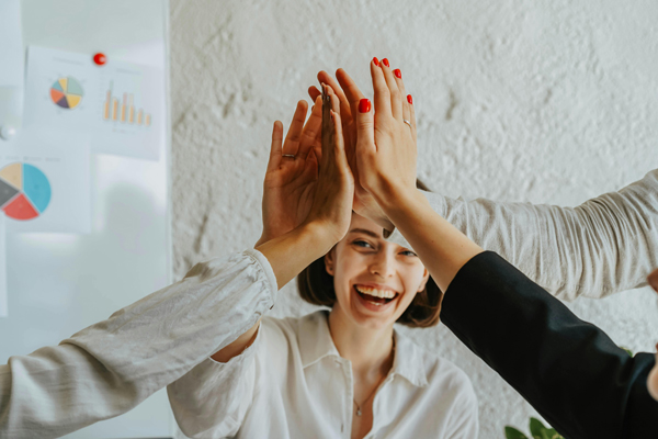 Teamwork und Erfolg, motiviertes Team gibt sich ein High-Five in einem modernen Büro in Hamburg.